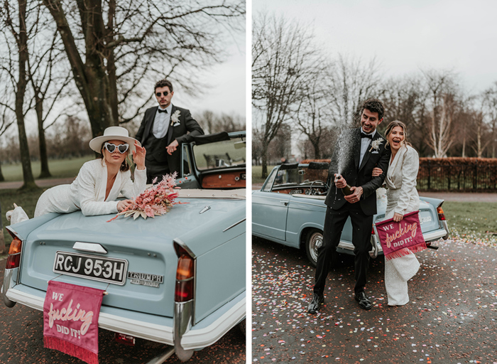 On the left, woman in a white suit, sunglasses and hat leans on a blue convertible car while a man in a suit leans on the car further in the distance, on the right the same couple stand in front of the car and spray a bottle of champagne