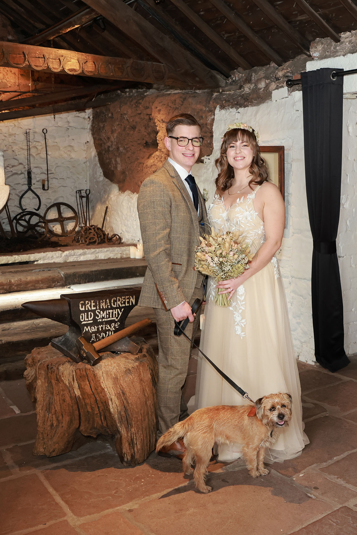 bride and groom smile next to their dog after wedding at gretna green