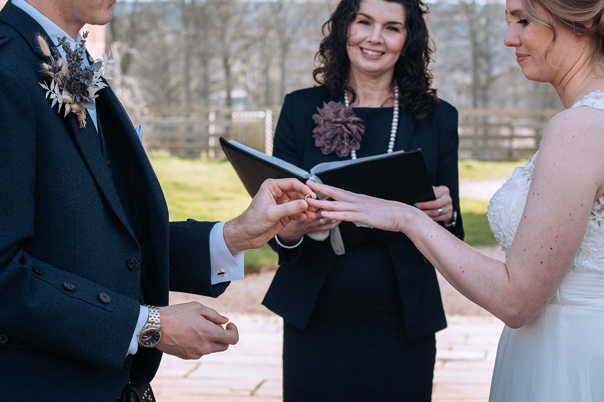 Groom puts brides wedding ring on at altar