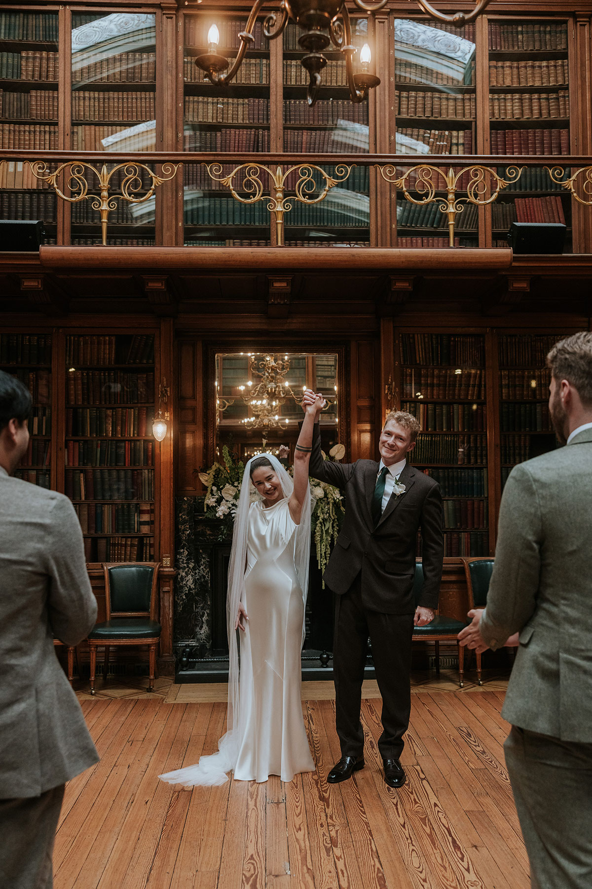 Newlyweds celebrating at the altar with raised hands in library wedding venue.