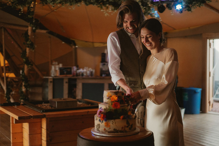 A Bride And Groom Cutting A Wedding Cake In A Tipi At Hartree Estates