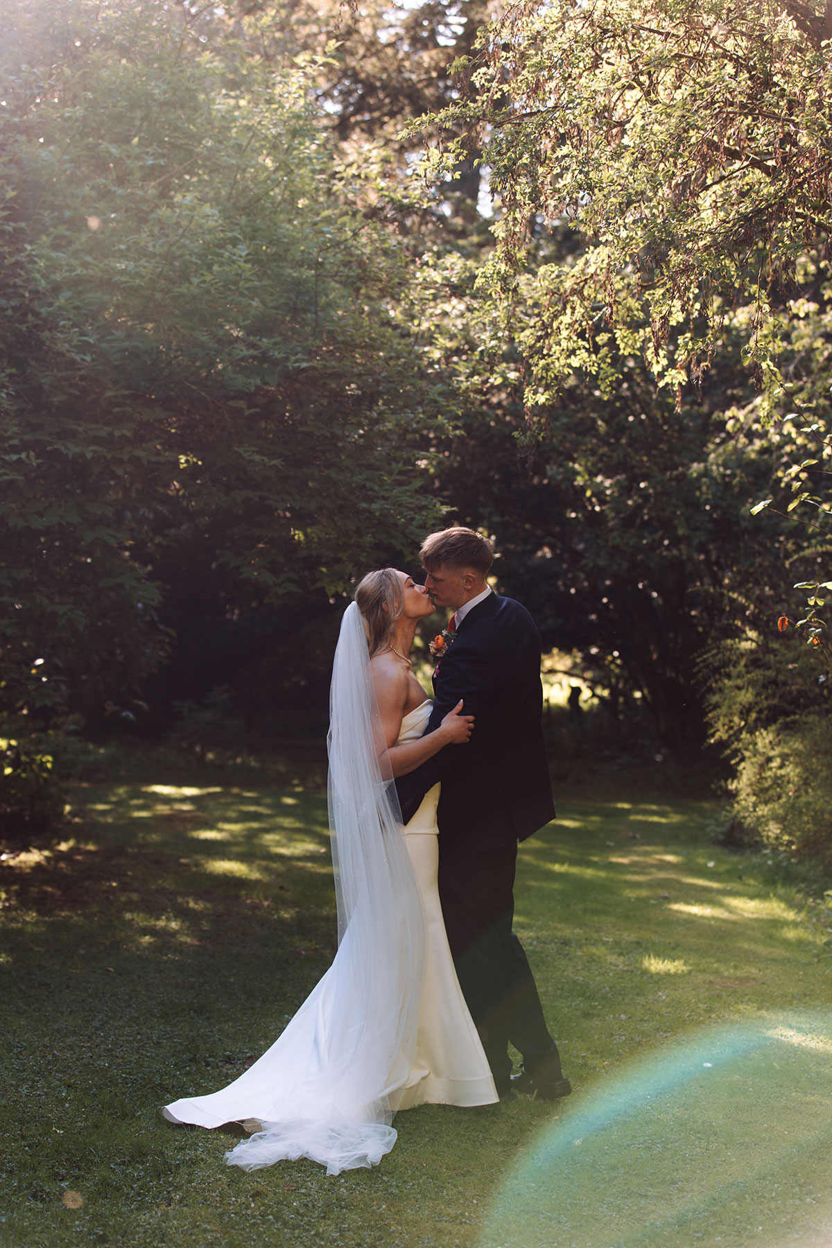 Bride and groom kissing in woodland garden setting at Rosebery Estate wedding venue