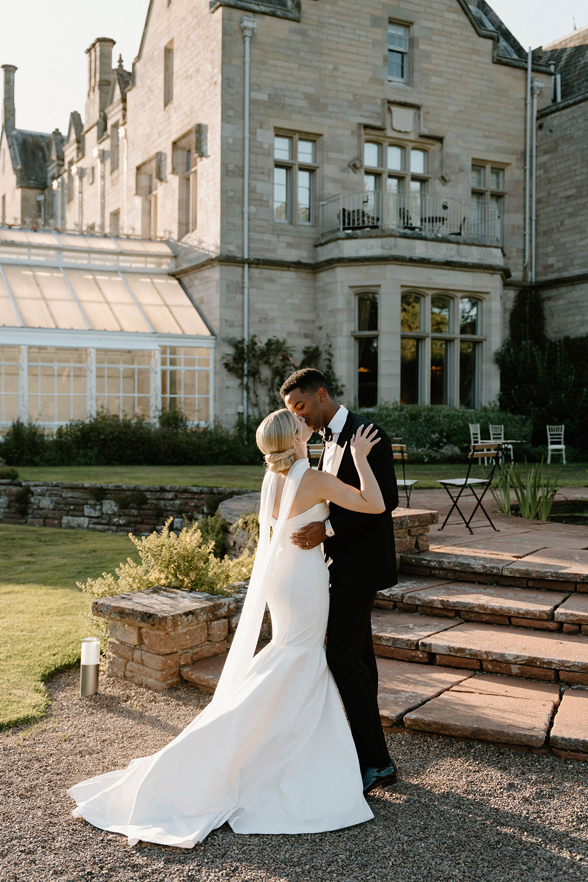 Newlywed couple embracing outside a historic Scottish country house wedding venue during golden hour portraits