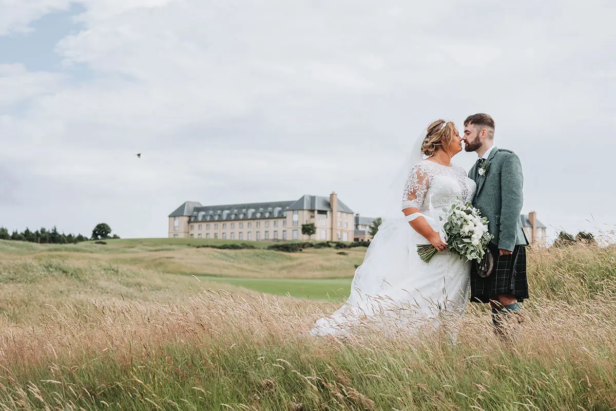 Couple in wedding outfits standing on grass