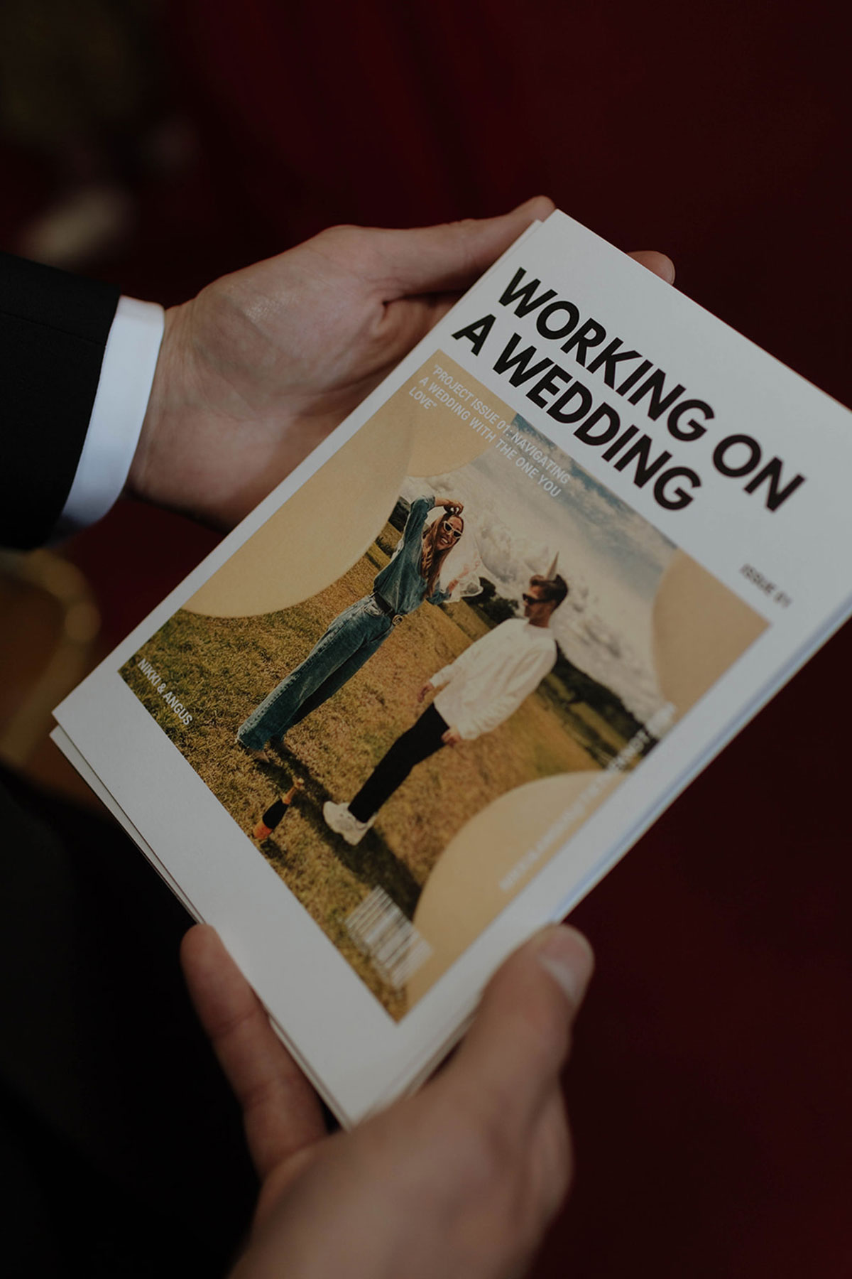 Close-up of hands holding a ‘Working on a Wedding’ booklet during a wedding ceremony.