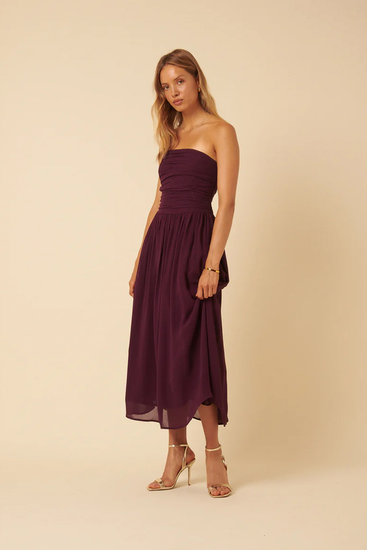 Model wearing a purple bandeau midi dress with a ruched bodice and softly flowing skirt.