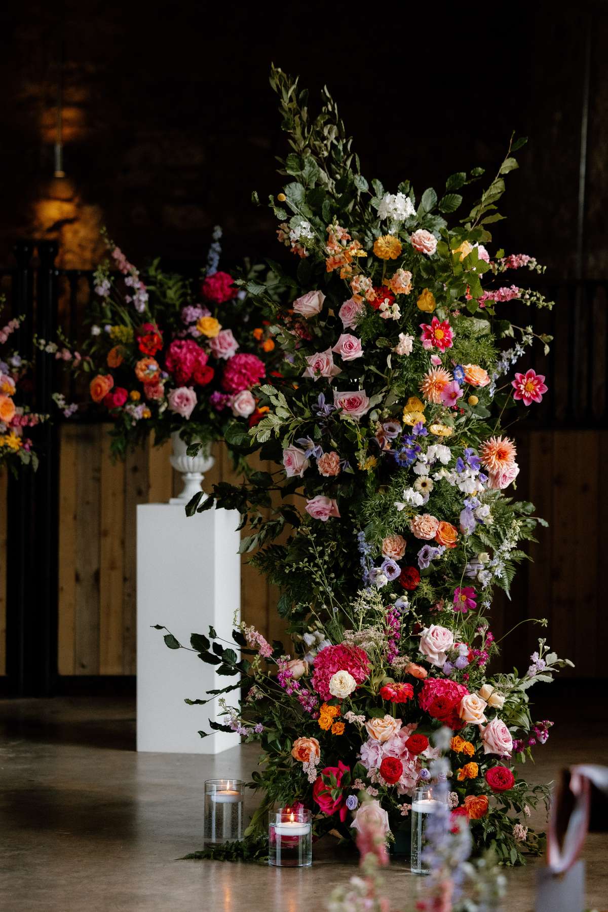 Large colourful floral ceremony arrangement with candles at Falside Mill wedding venue in Fife
