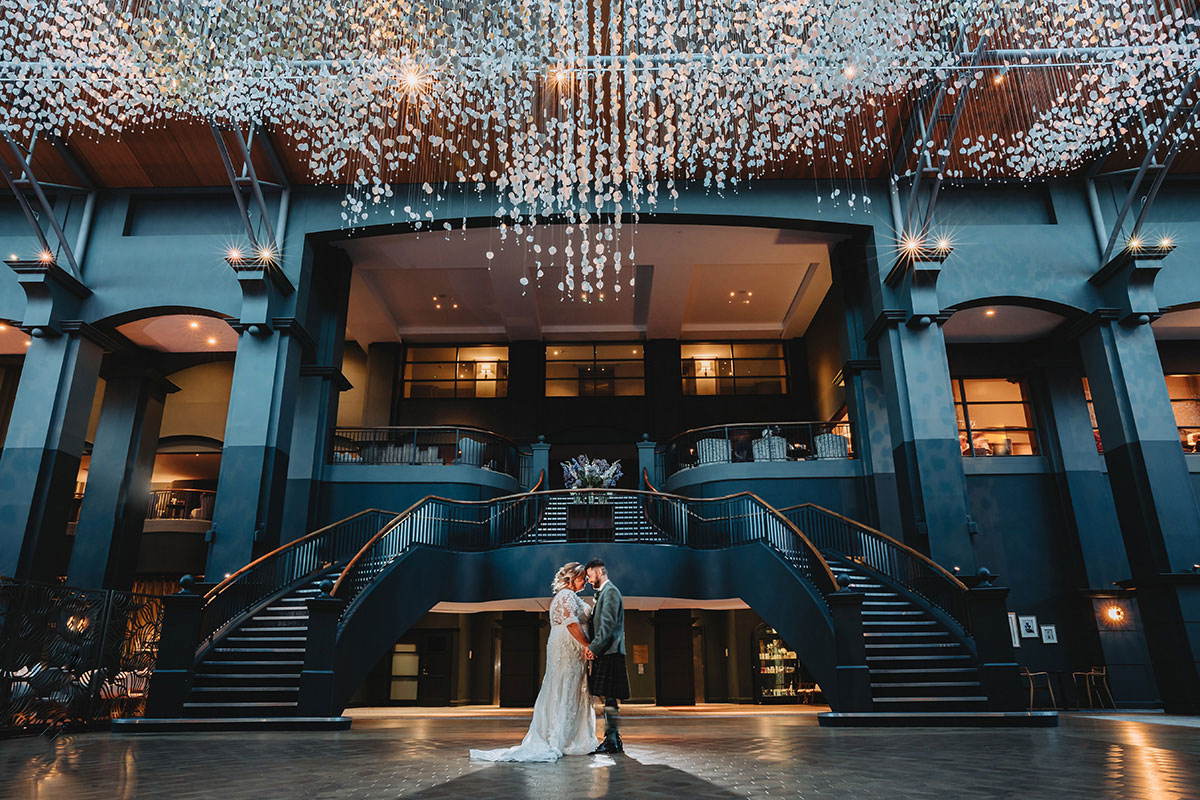 Bride and groom embracing beneath cascading floral ceiling in Fairmont St Andrews ballroom