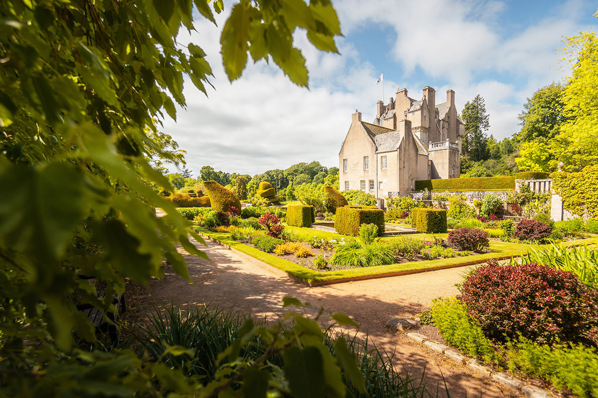 Formal gardens at Crathes Castle featuring topiary, flower beds, pathways and views of the castle in Aberdeenshire