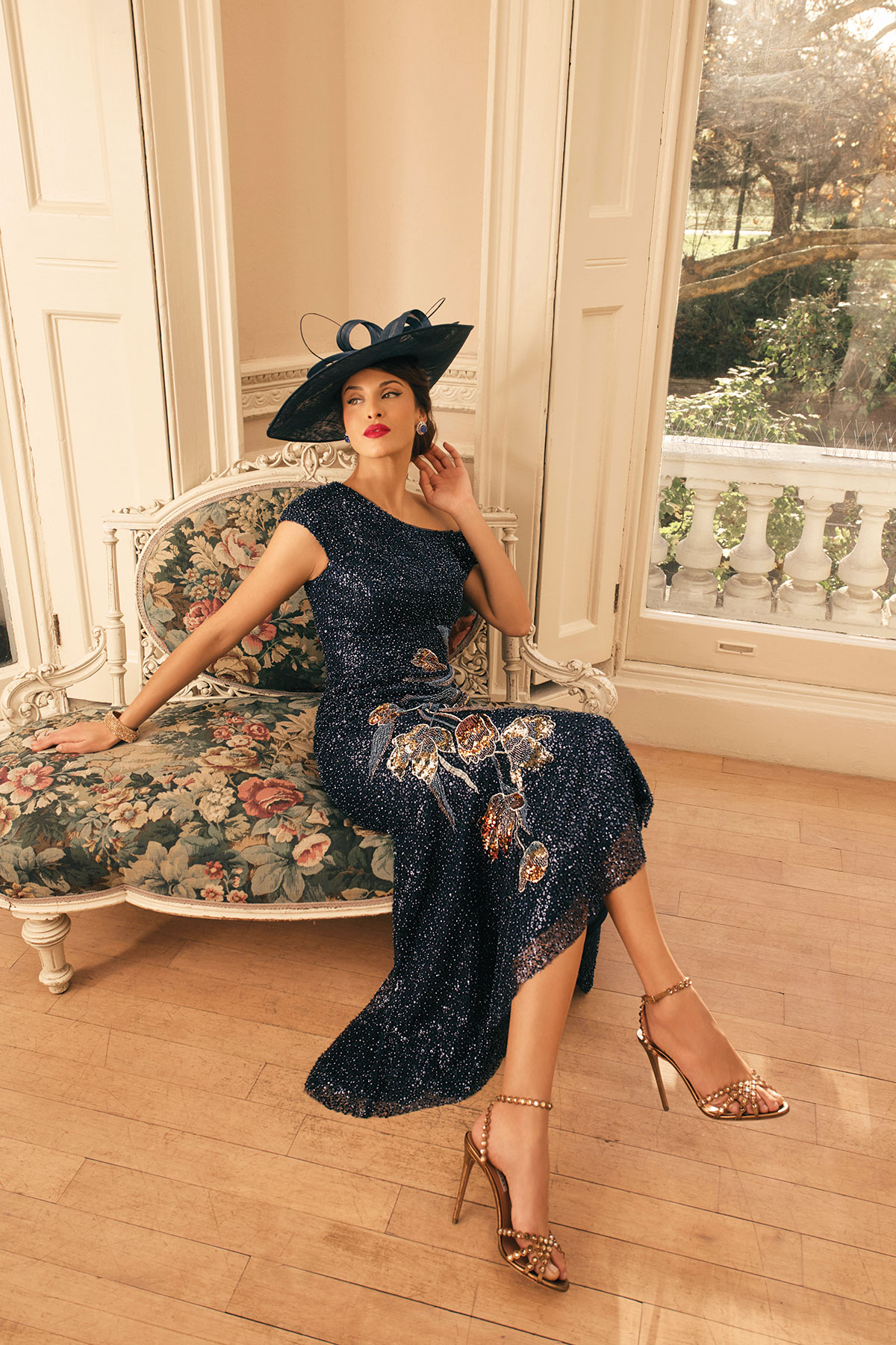 Navy embellished mother of the bride dress with floral detailing, styled with a black occasionwear hat.