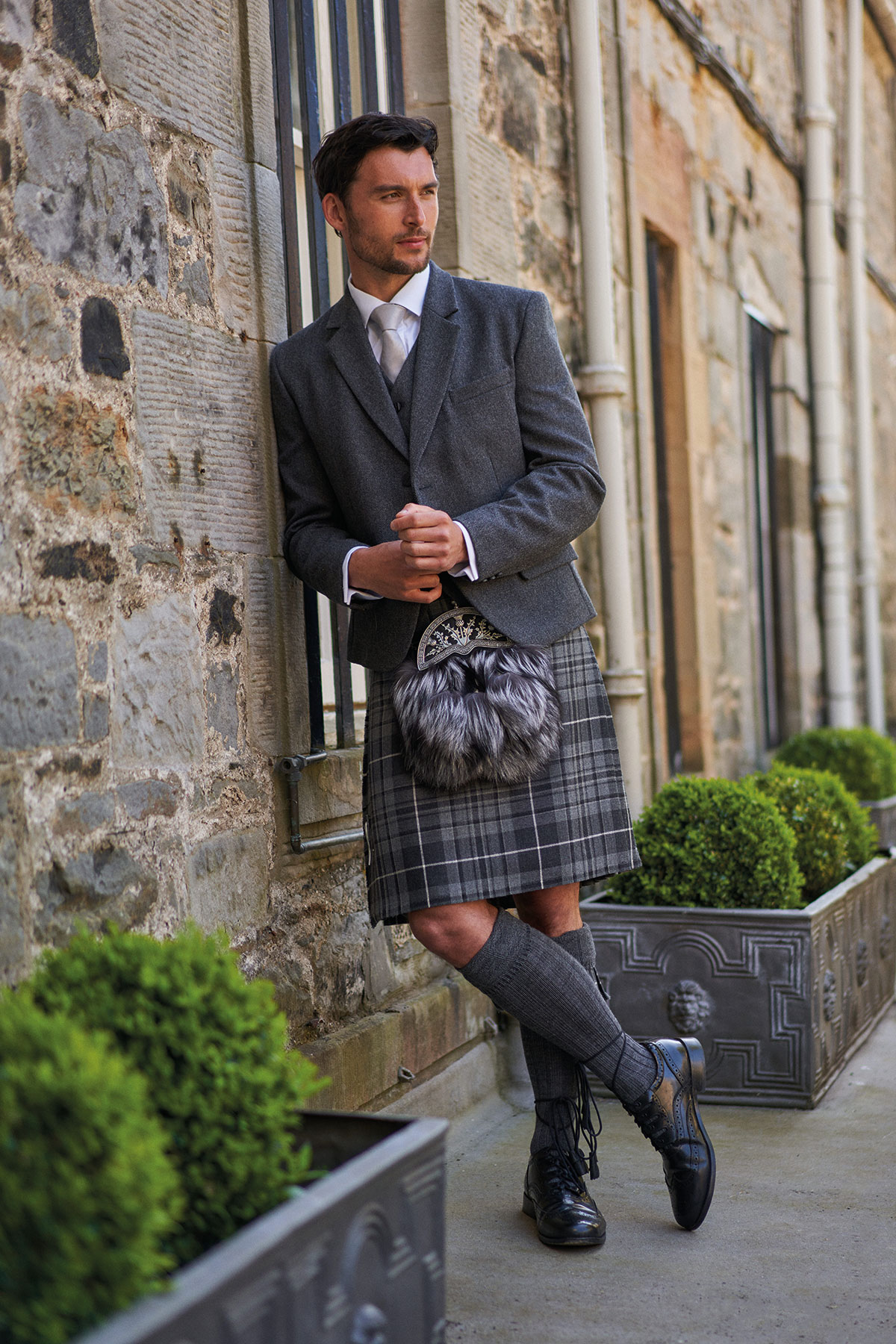 Groom wearing a grey jacket with tartan kilt and dress sporran for a Scottish Highlandwear wedding outfit