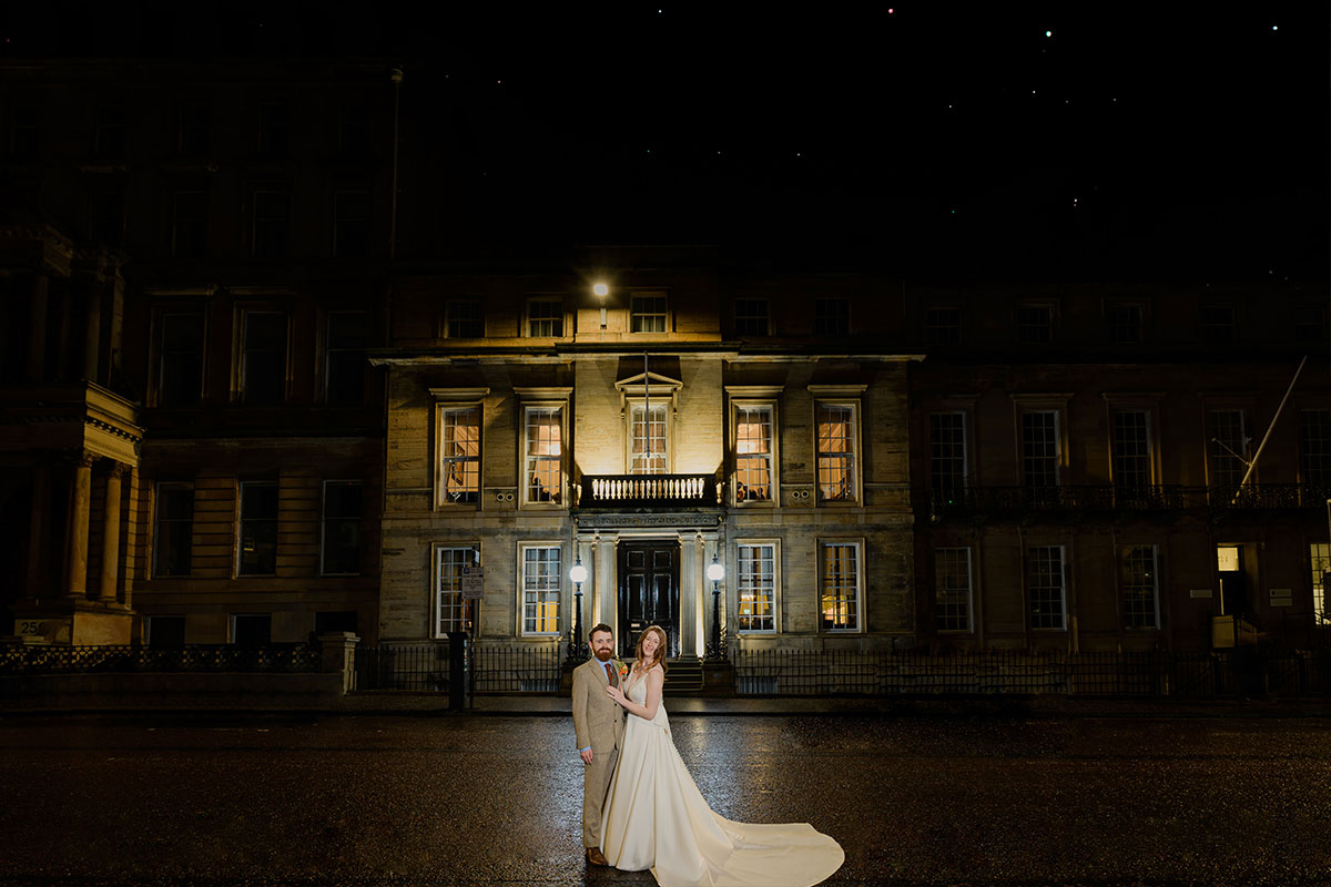 a couple standing in front of an illuminated building at night