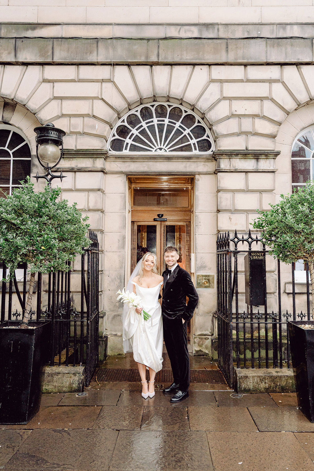 Couple standing outside the entrance of The Signet Library on a rainy wedding day