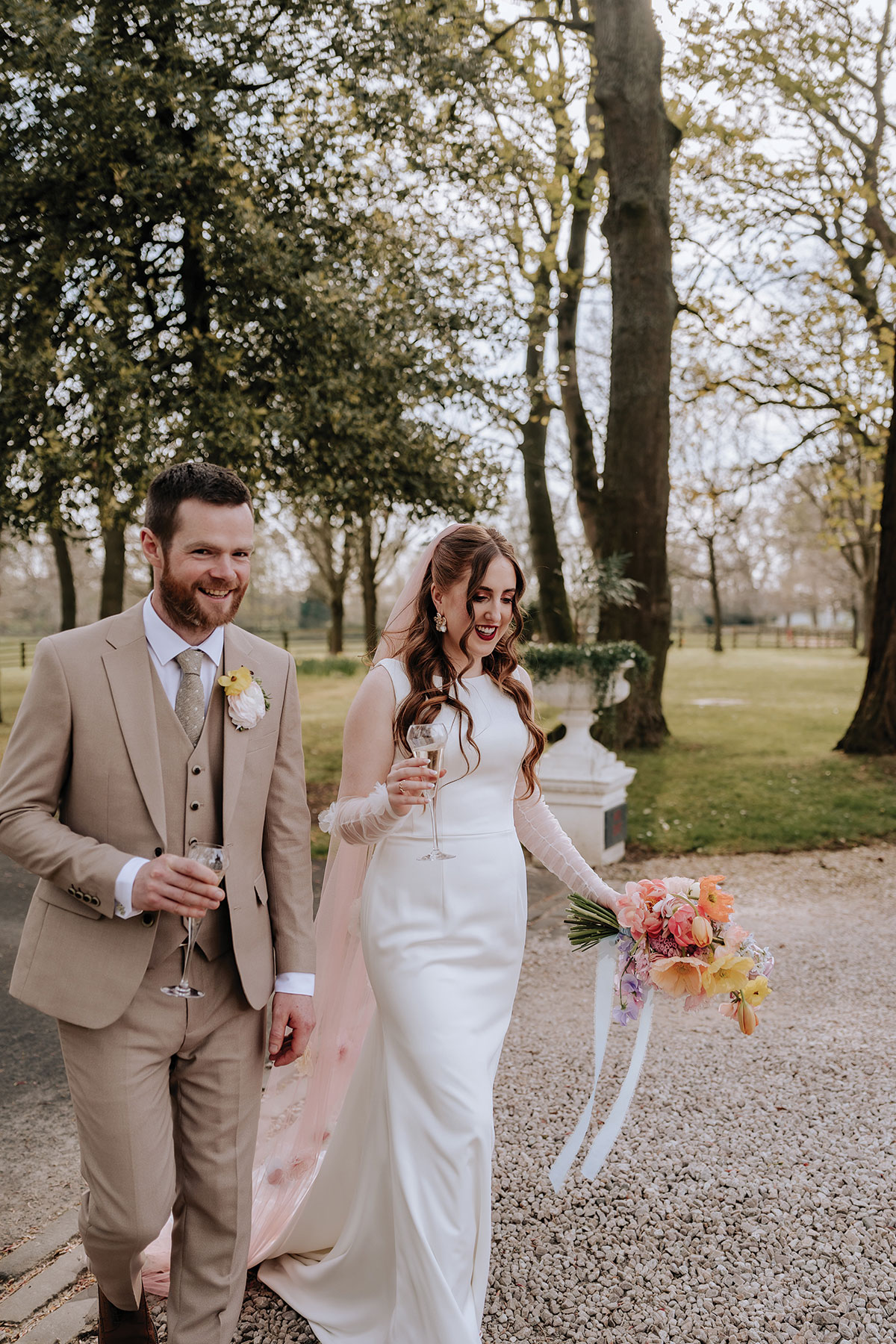 a bride and groom walking hand in hand in gardens of Carlowrie Castle