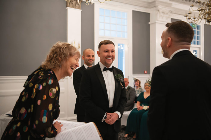 celebrant laughs with couple during wedding ceremony