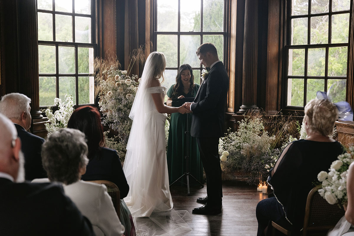 Indoor wedding ceremony in Music Room with floral arrangements at Gilmerton House