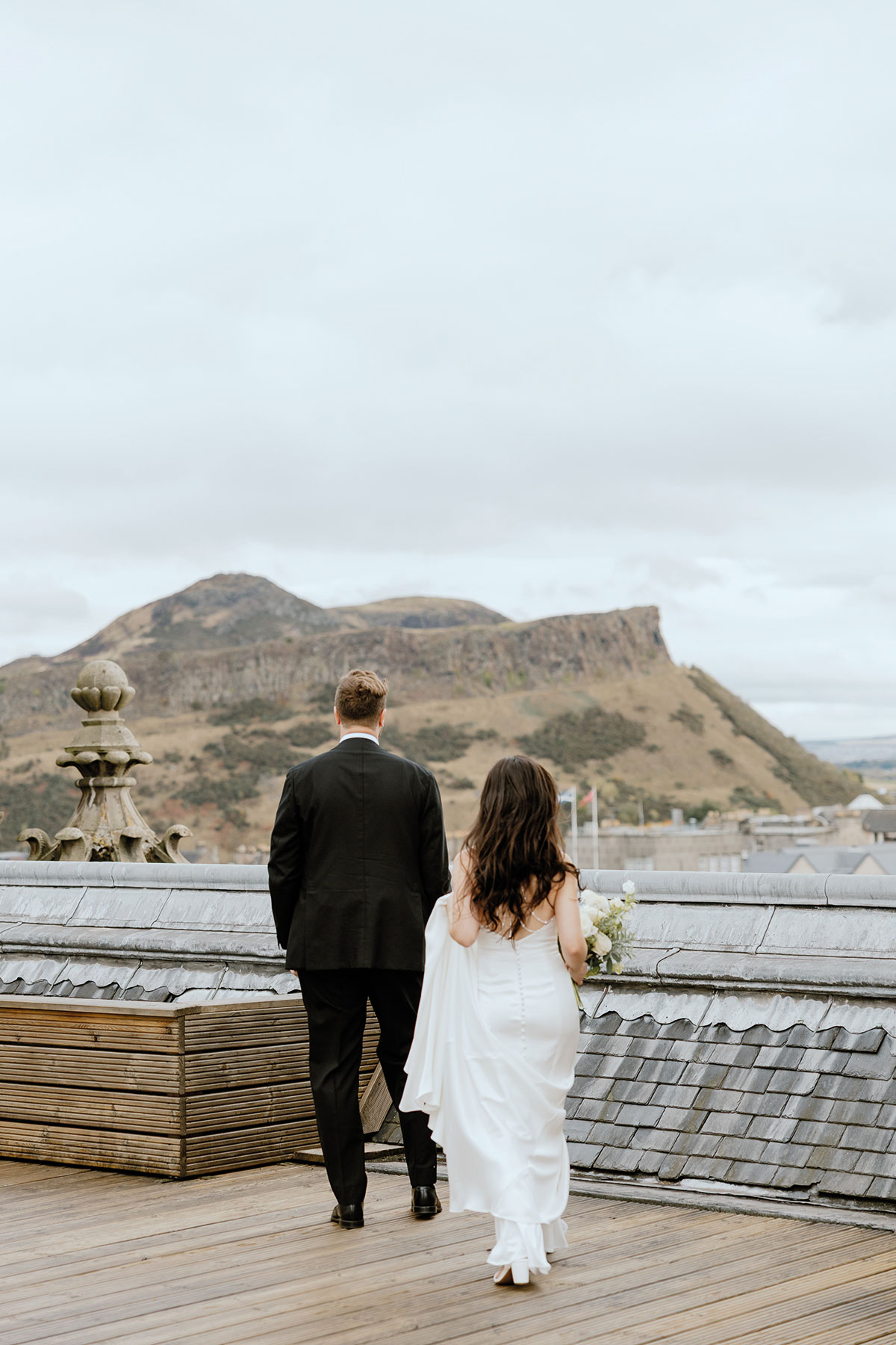 Newlyweds enjoying The Balmoral's private rooftop terrace overlooking Arthur's Seat in Edinburgh after their wedding ceremony