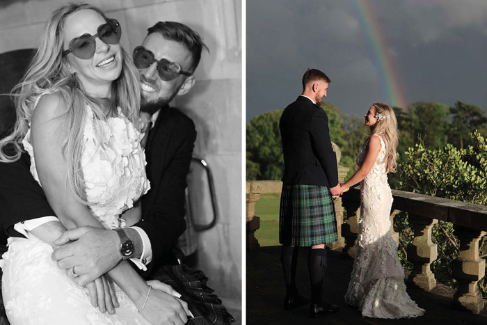 A Bride Sitting On A Groom's Knee Wearing Suglasses And Bride And Groom Posing Against A Grey Sky With Rainbow In Background