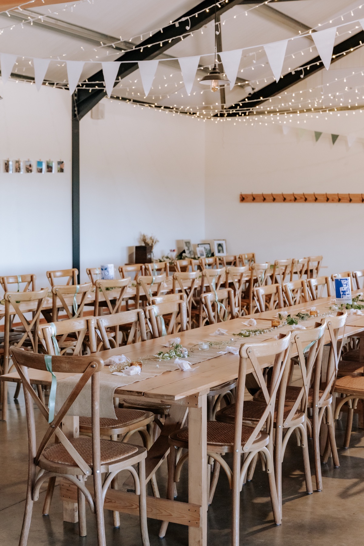 Wedding reception setup at Harvest Moon with long wooden tables, bunting and fairy lights.