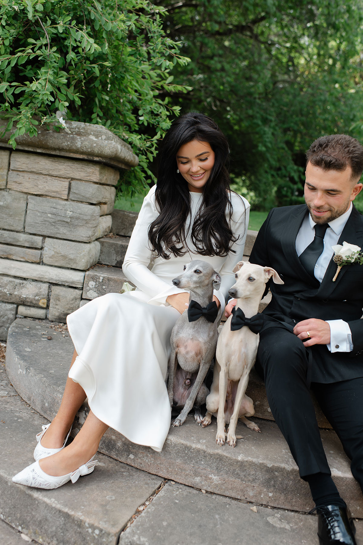 Newlyweds sitting together with their two dogs in bow ties at Carberry Tower, East Lothian