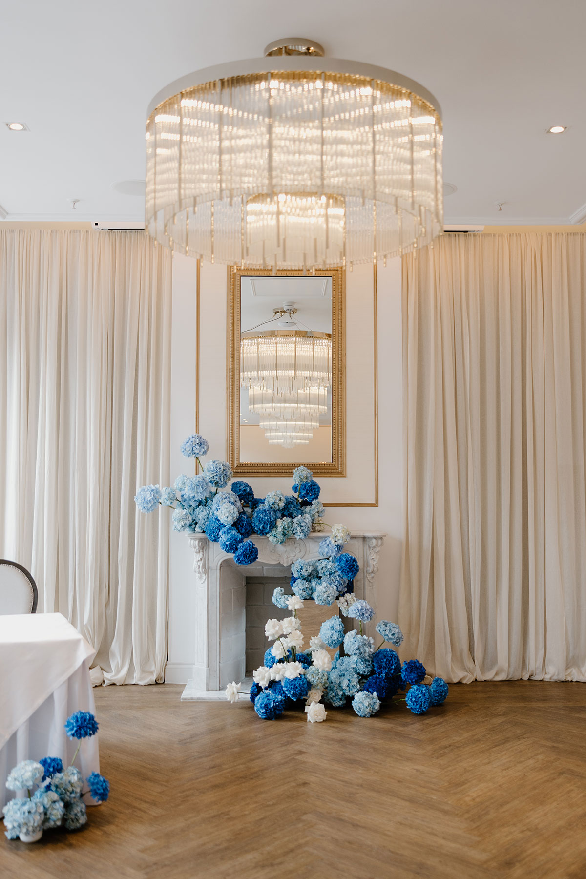 Ceremony backdrop at The Exchange Glasgow featuring chandelier lighting and dramatic blue hydrangea floral installation around fireplace