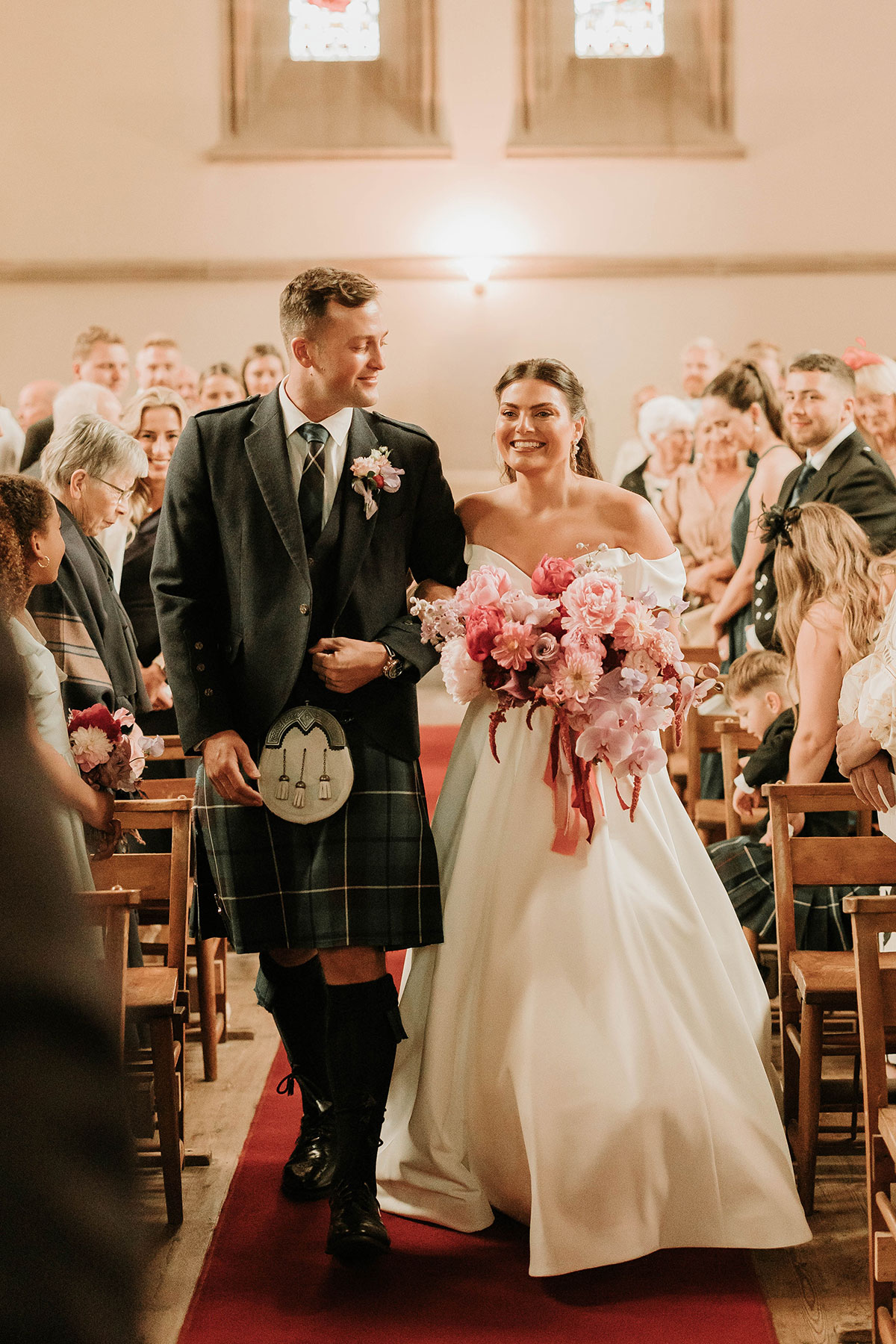 Bride walking down aisle with her brother at St Palladius Church during Drumtochty Castle Aberdeenshire wedding
