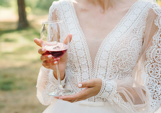 Woman wearing white lace dress holding red wine glass