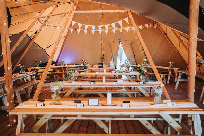 A tent set for a wedding with tables and chairs at John Muir Alpacas.