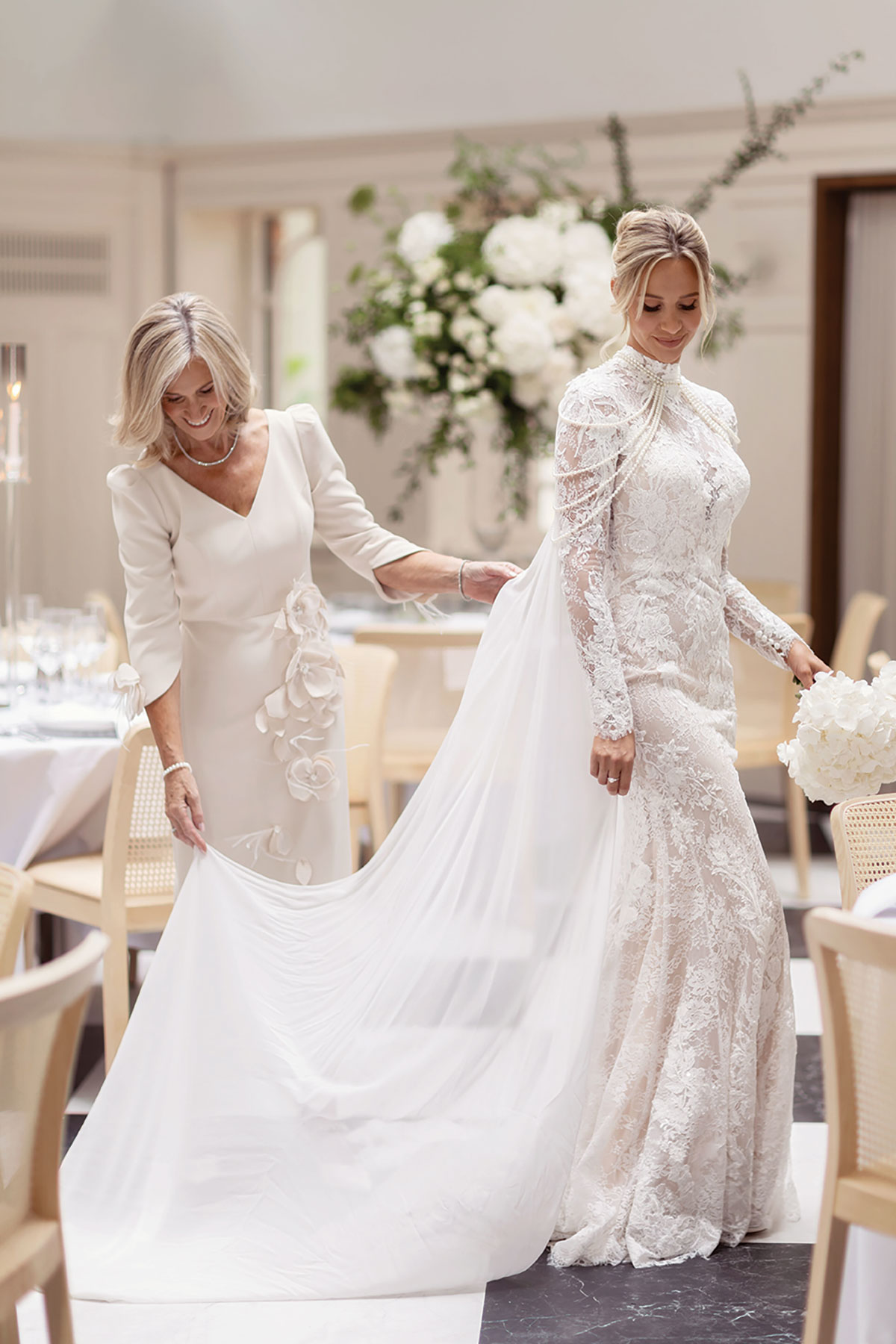 Mother of the bride adjusting lace bridal gown train during styled wedding shoot
