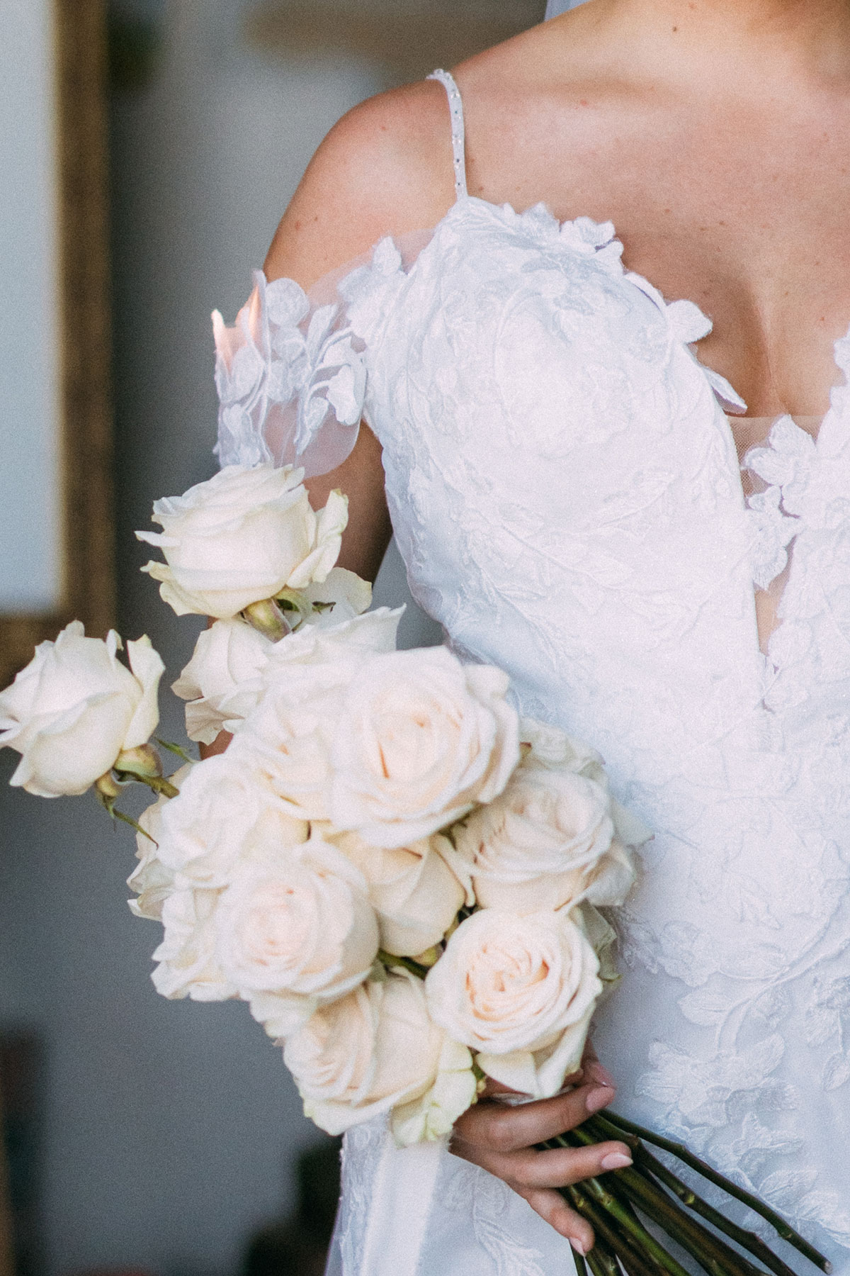 Bride holding white rose bouquet with lace wedding dress detail at Antico Borgo San Lorenzo Tuscany