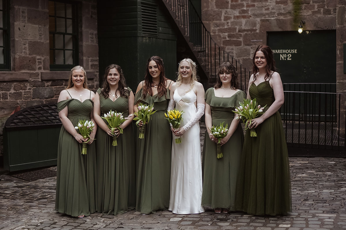 Bride and bridesmaids posing in the historic courtyard at Verdant Works wedding venue in Dundee.