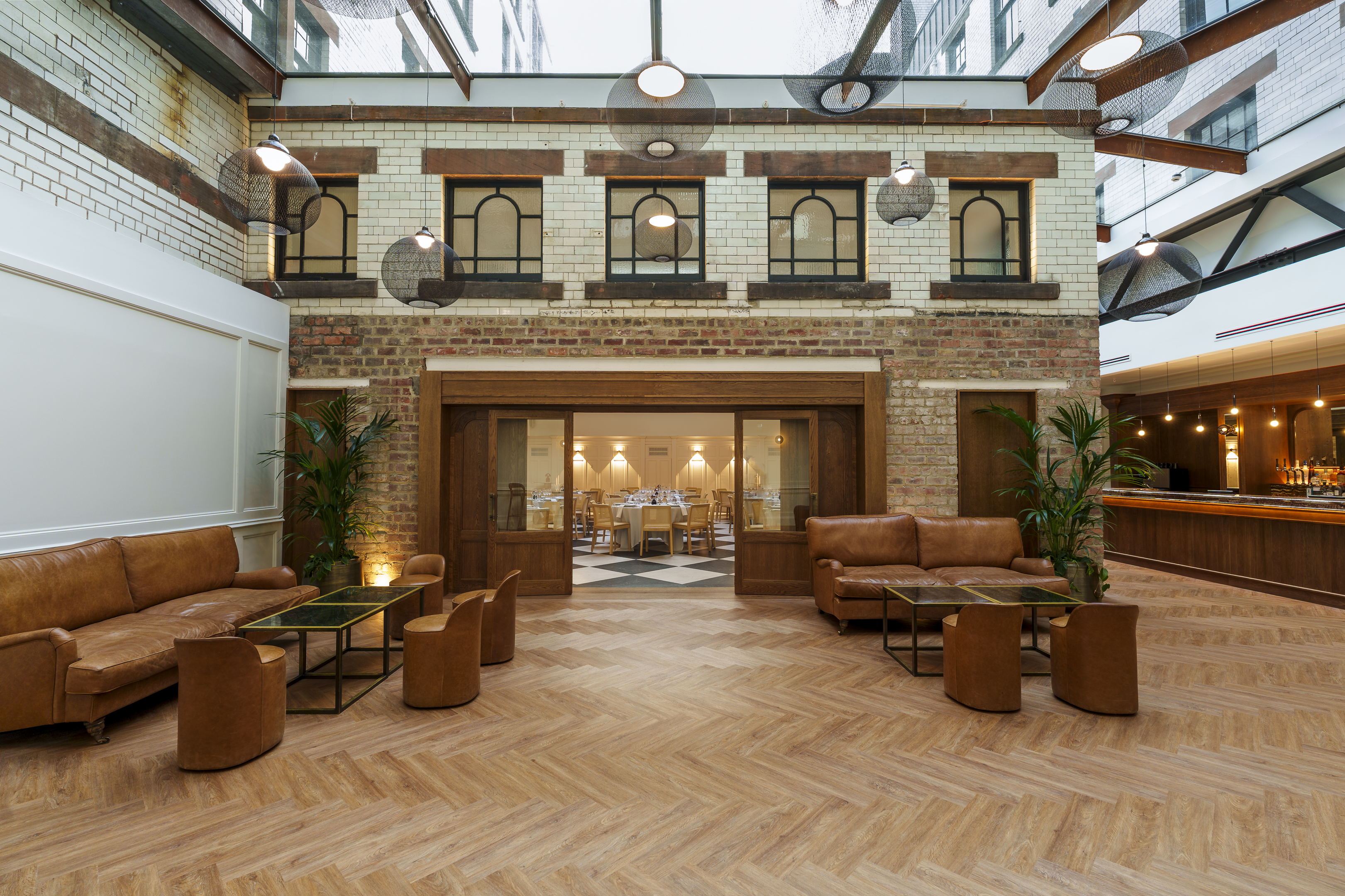 The Courtyard at The Collector's Hall with an all-weather glass canopy, herringbone flooring and tan leather couches