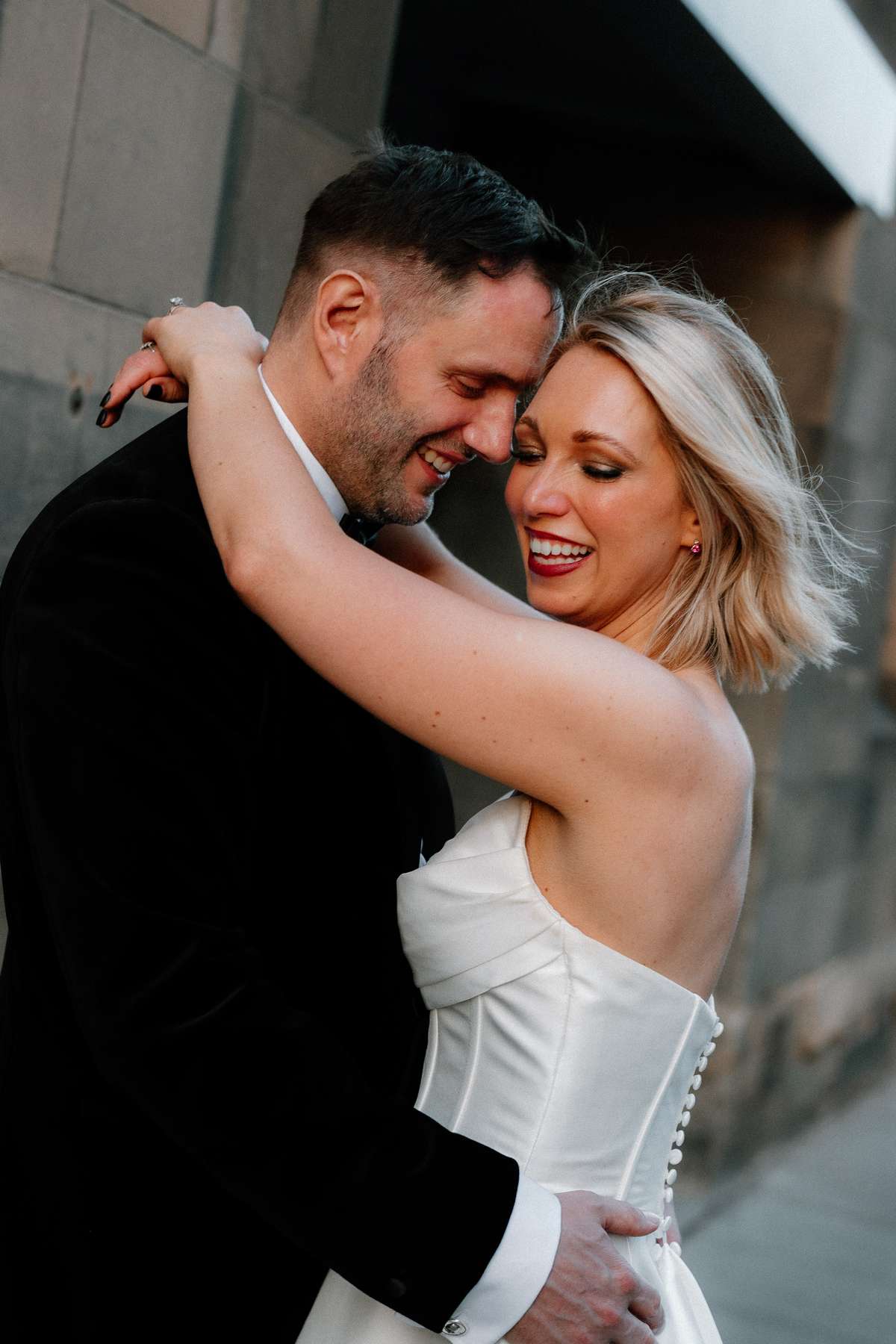 Kara and Rory smile and embrace during their wedding portraits on the streets of Edinburgh.