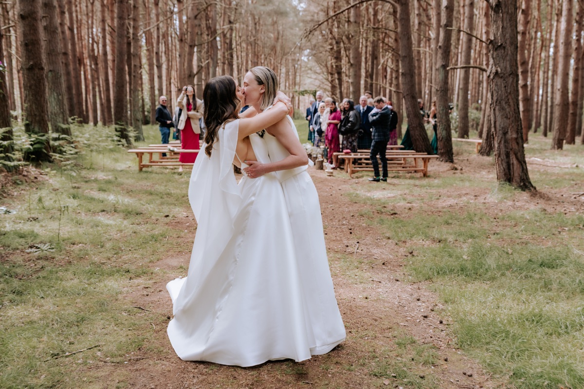 Hannah and Donna kissing in the woodland after their wedding ceremony at Harvest Moon.