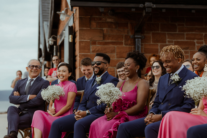 Wedding Guests Wearing Pink Dresses And Navy Suits Laughing At Dougarie Boathouse