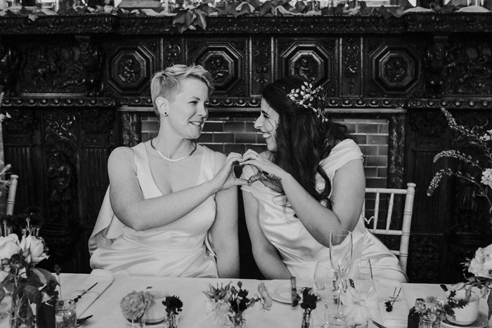 black and white photograph of two brides on wedding day at cambo house and estate doing a love heart sign with their hands