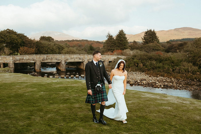 bride and groom walk hand in hand on grass at dougarie boathouse