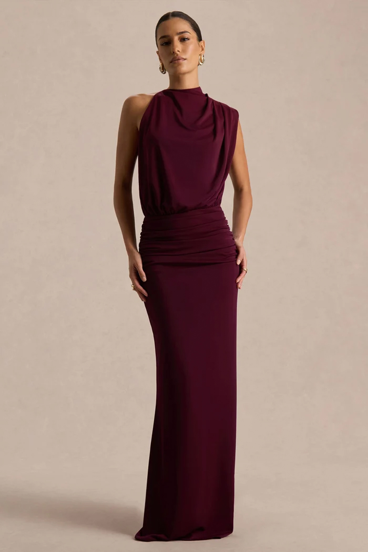 Model wearing a burgundy high-neck maxi dress with draped detailing, ruched waist and floor-length skirt.
