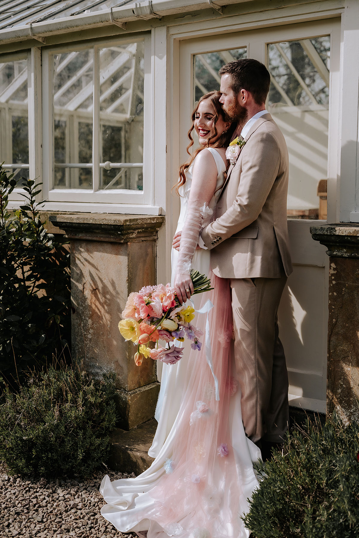 a bride and groom posing by a glasshouse at Carlowrie Castle edinburgh wedding venue