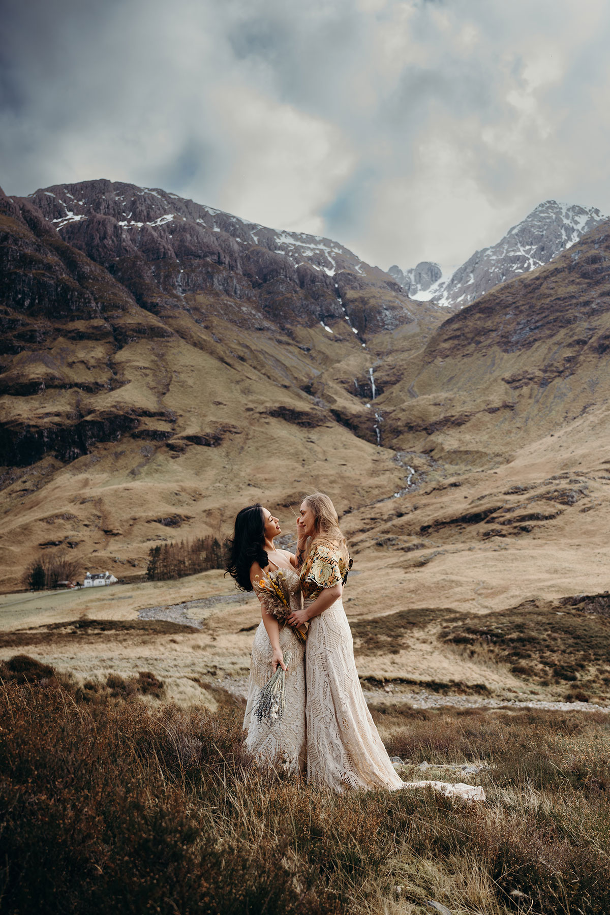 Couple posing together in boho lace wedding dresses during an outdoor Scottish elopement shoot in Glencoe.