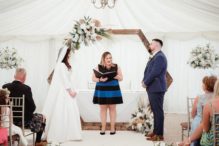 Bride and groom stand at altar with celebrant under hexagon arch