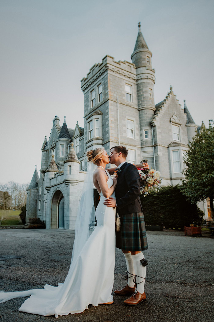 exterior shot of ardoe house in aberdeen with bride and groom kissing outside