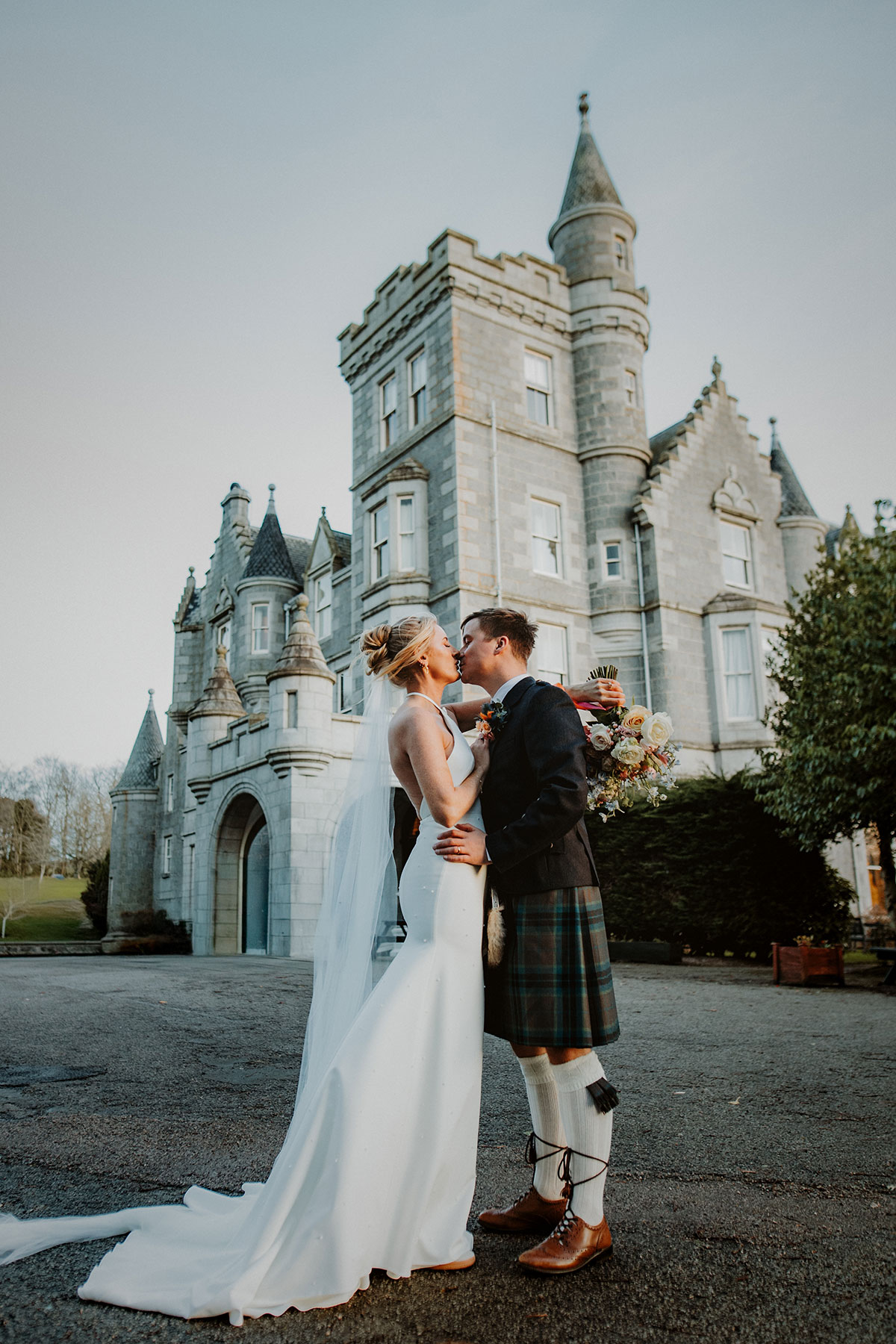 exterior shot of ardoe house in aberdeen with bride and groom kissing outside