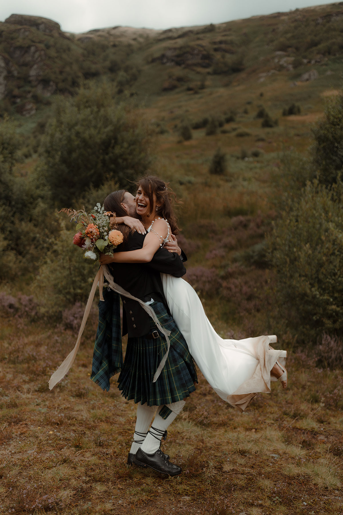 a groom lifting and swinging a bride in countryside at Carrick Castle Estate