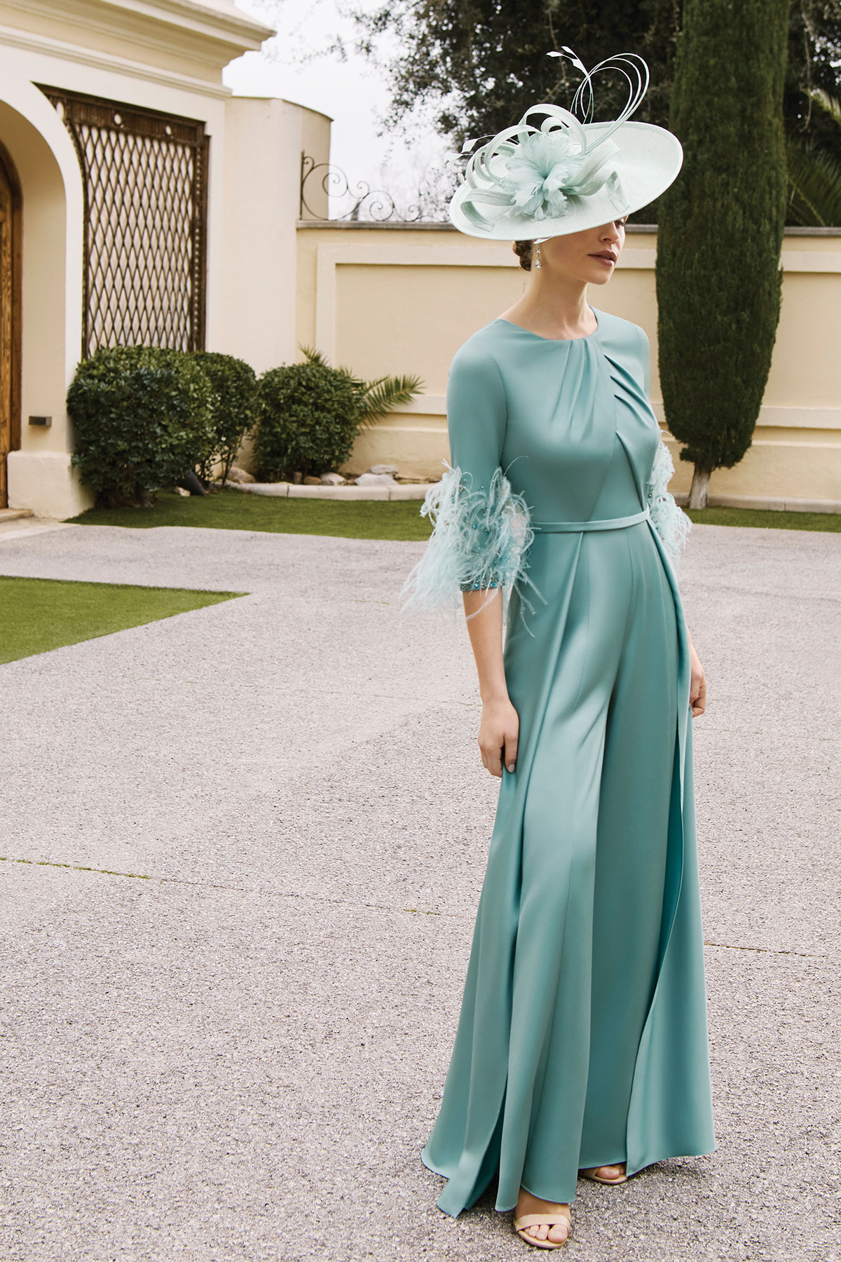 Pale blue mother of the bride dress with feather-trim sleeves and a large coordinating hat.