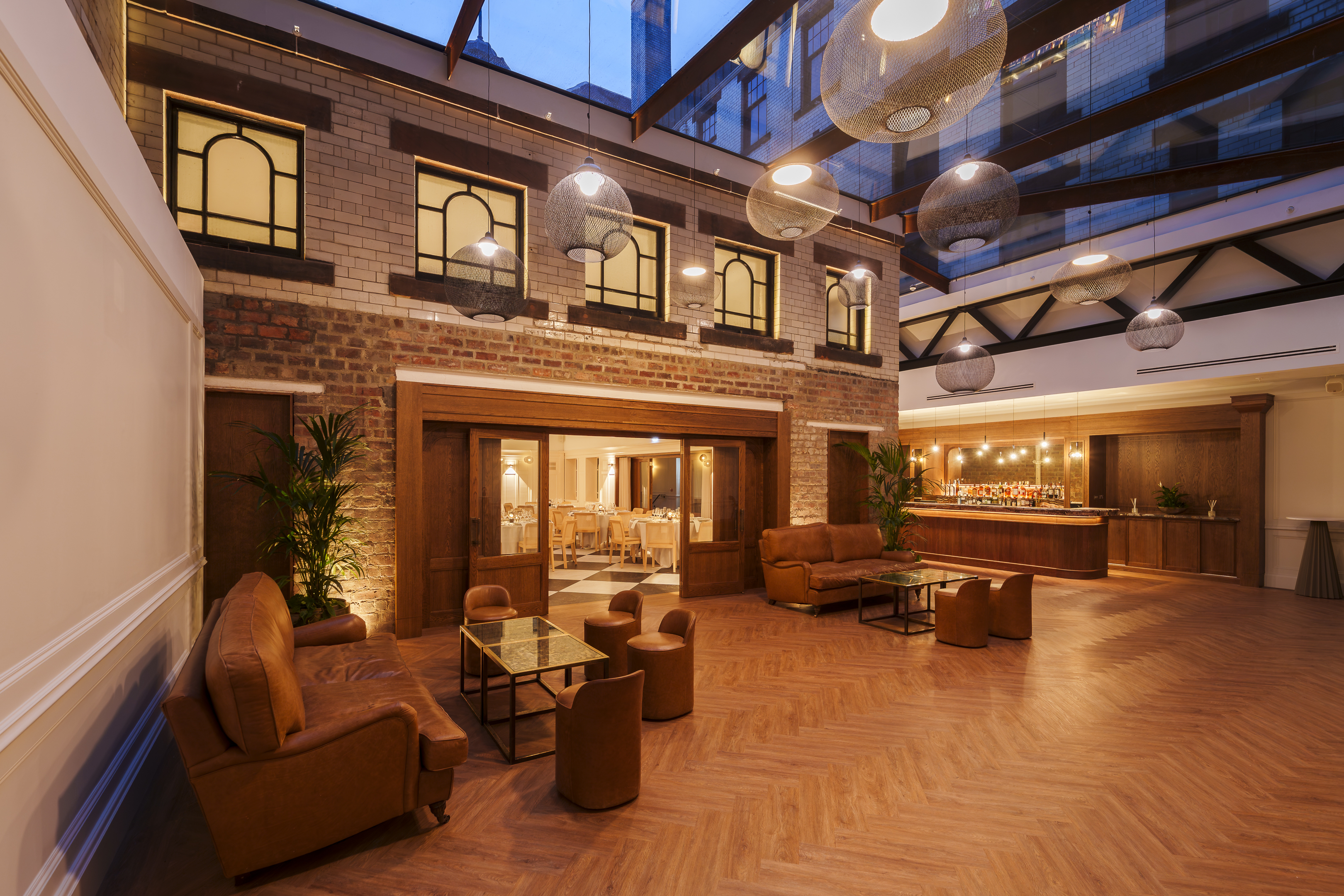the courtyard at the collector's hall at night with bar in the background and cleared floor space with herringbone flooring