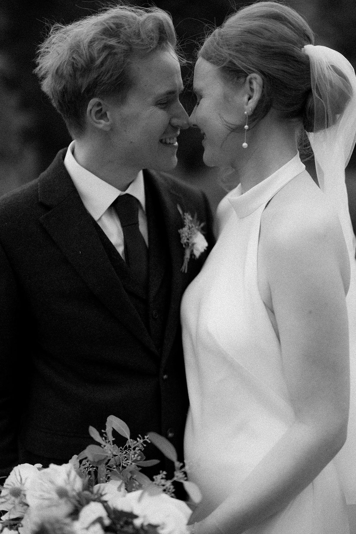Black and white close-up of bride and groom smiling nose to nose on wedding day