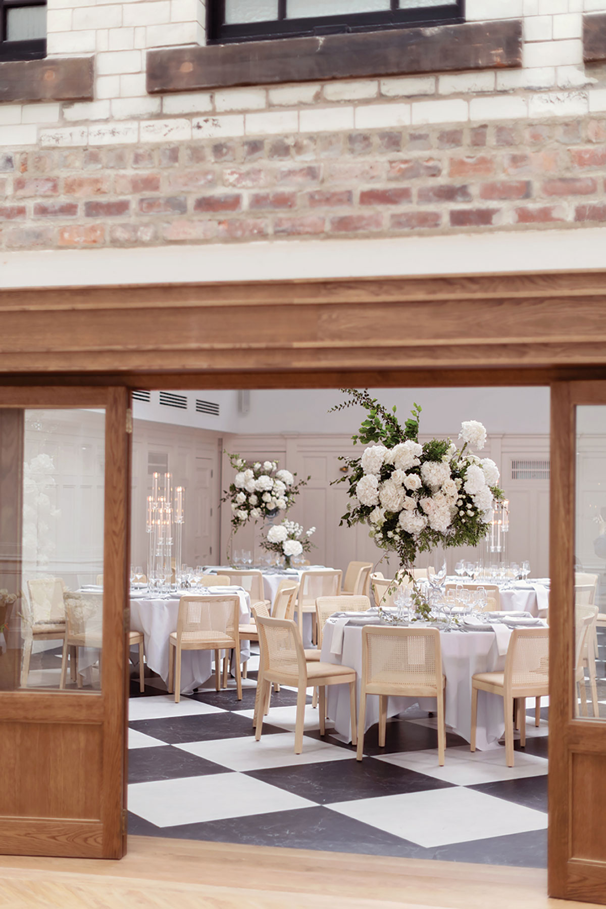Wedding reception setup with round tables, tall white floral centrepieces and candlelight at modern venue