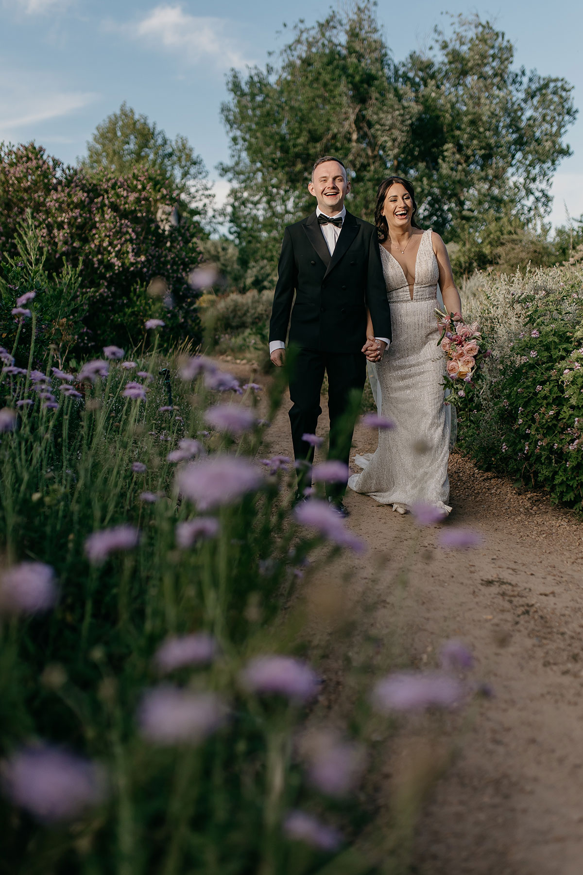  Bride and groom walking through the gardens at Boschendal Wine Estate during golden hour wedding portraits in Cape Town