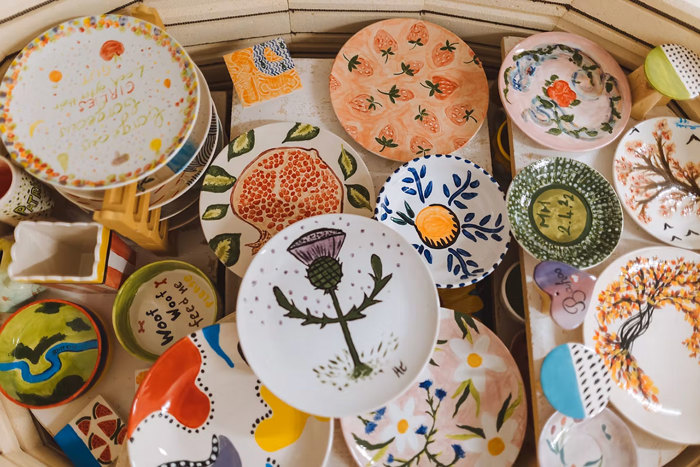 inside a kiln we see a finished assortment of glazed and painted plates, bowls, dog bowls, magnets and more